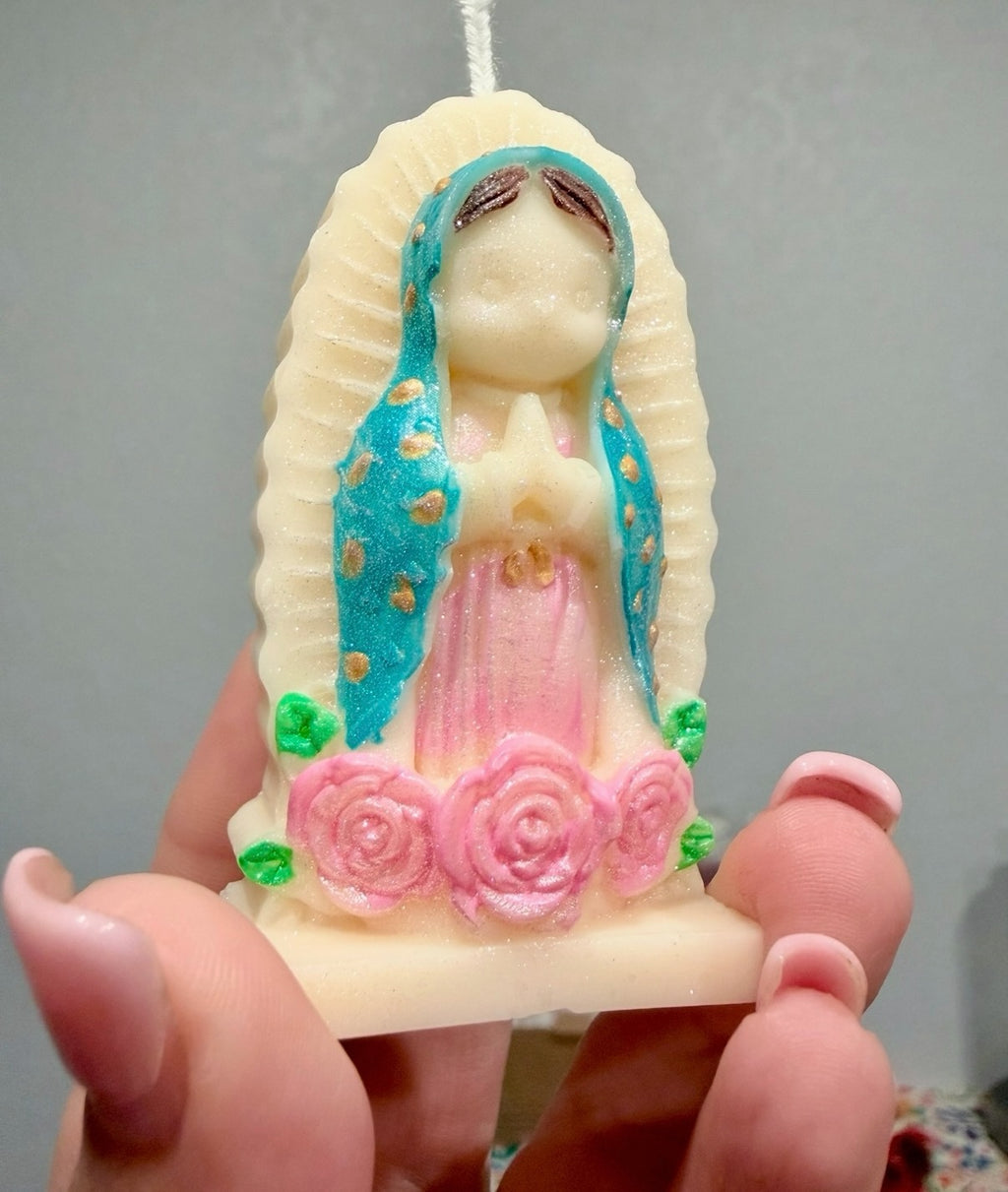 Trinity Candle Co. Our Lady of Guadalupe devotional candle with teal mantle, pink gown, and sculpted rose base.